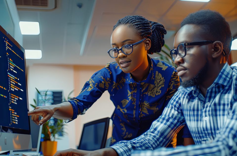 Two software testers african american young man and woman working in office with computer coding and pointing at monitor working together